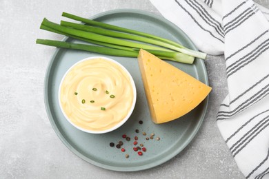 Photo of Tasty cheese sauce with green onion and peppercorns on light grey table, top view
