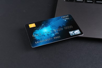 Photo of Credit card and laptop on grey table, closeup