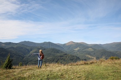 Photo of Young woman enjoying beautiful mountain landscape, back view