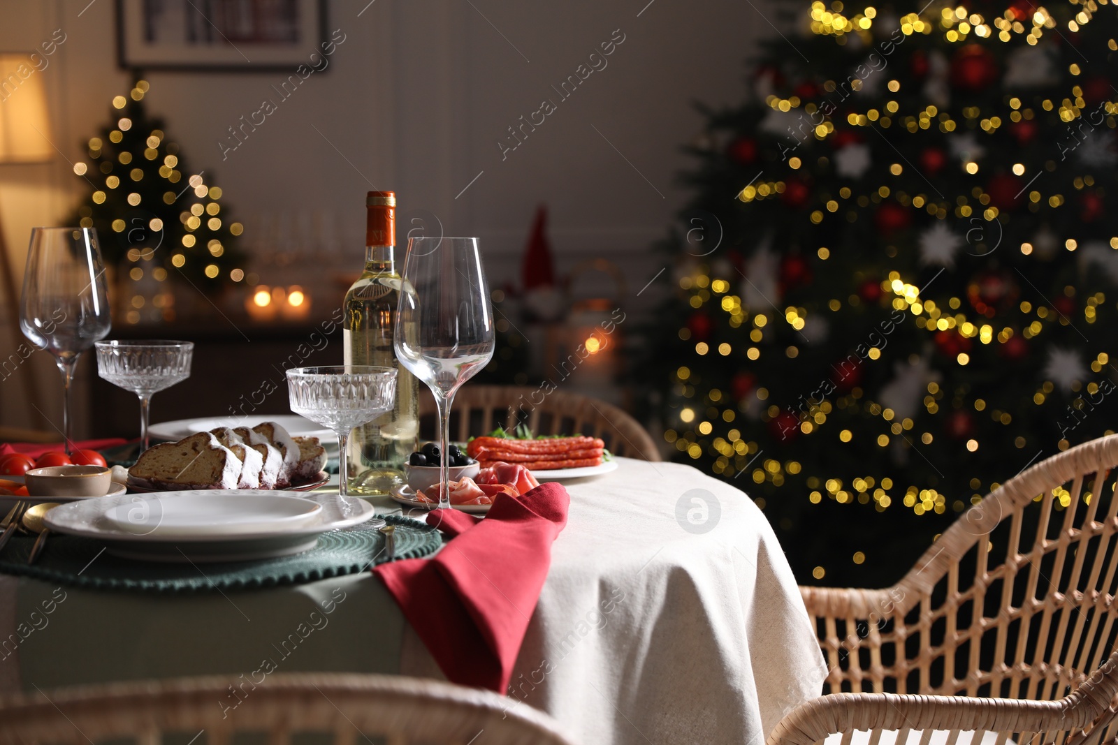 Photo of Christmas table setting with bottle of wine, appetizers and dishware indoors