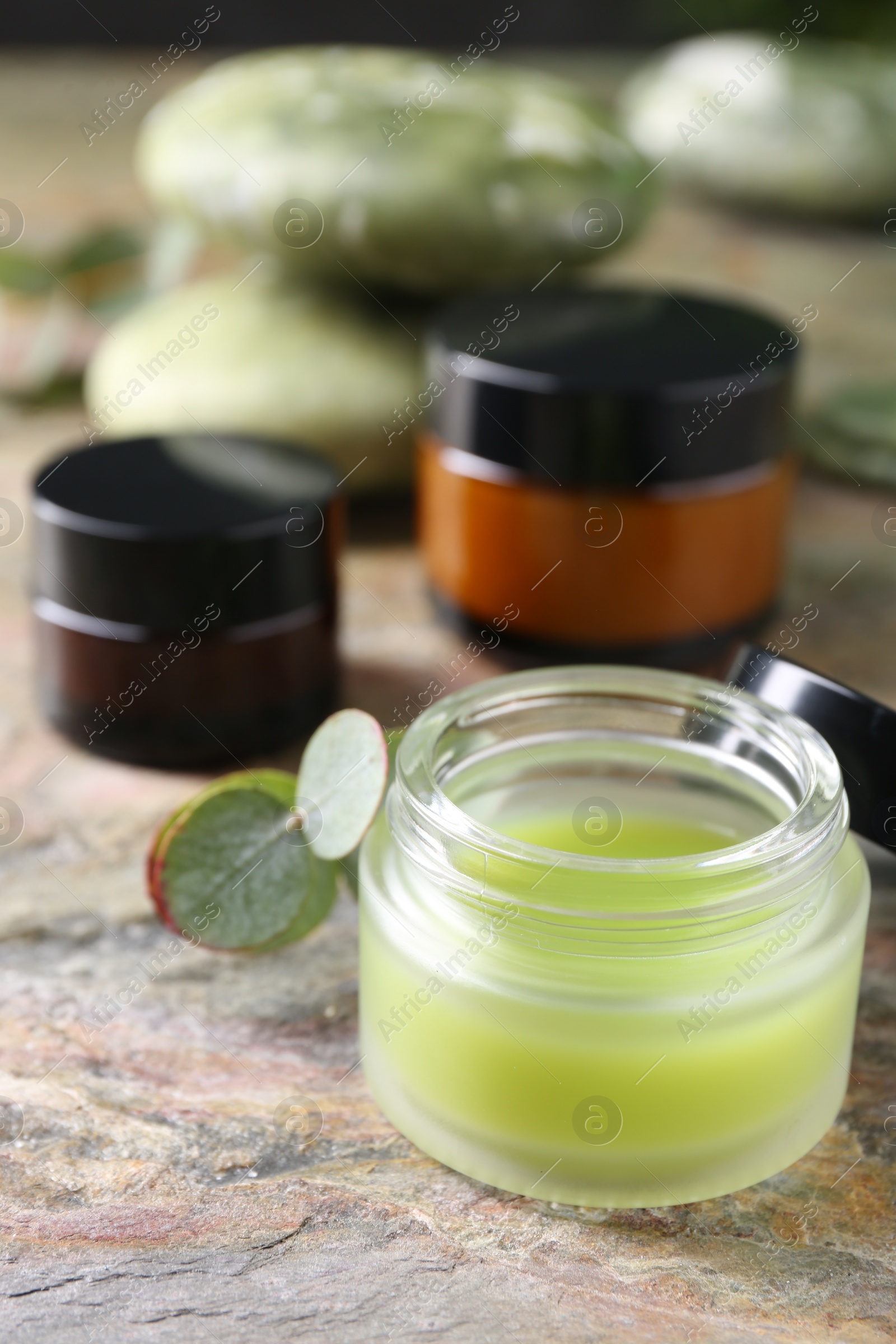 Photo of Jars of cream on textured table, closeup. Body care products