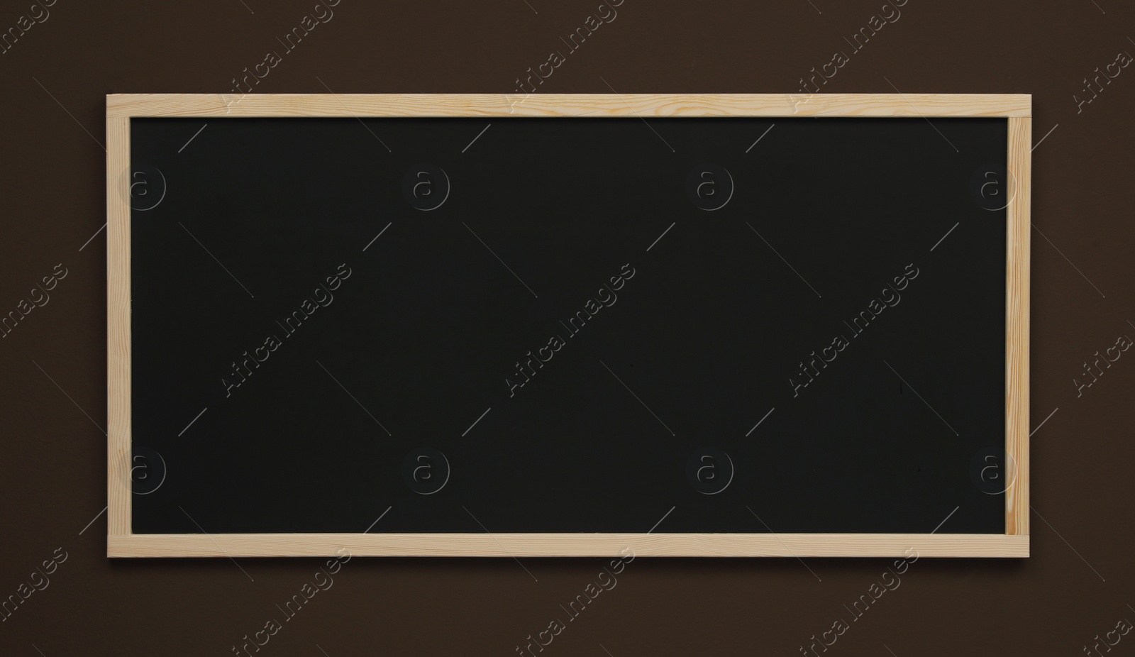 Photo of Clean black chalkboard hanging on brown wall