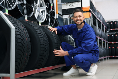 Photo of Male mechanic with car tires in auto store