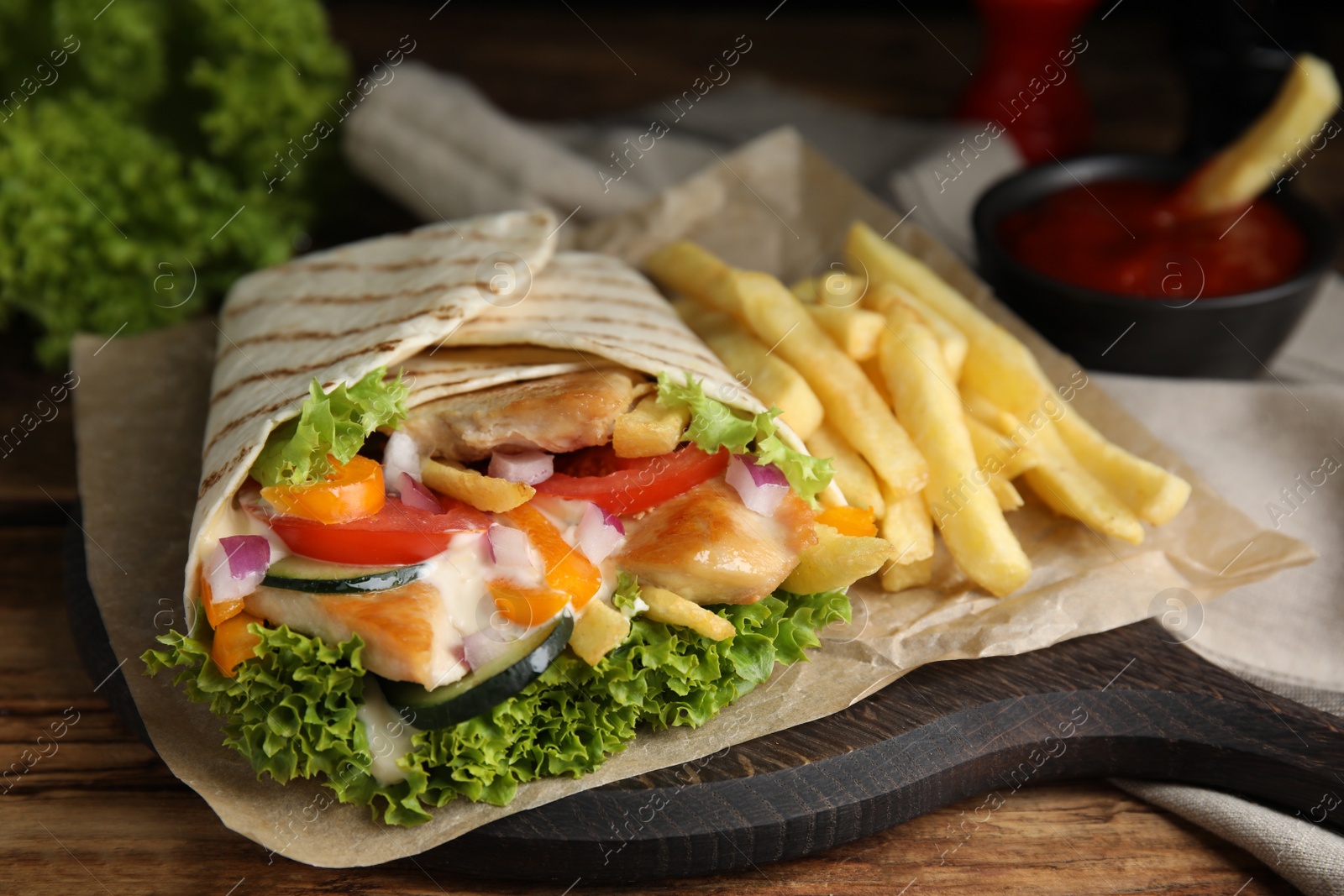 Photo of Delicious chicken shawarma and French fries on wooden table, closeup