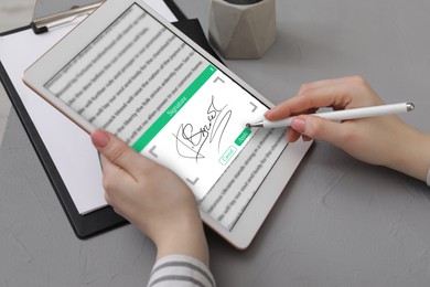 Image of Electronic signature. Woman using stylus and tablet at table, closeup