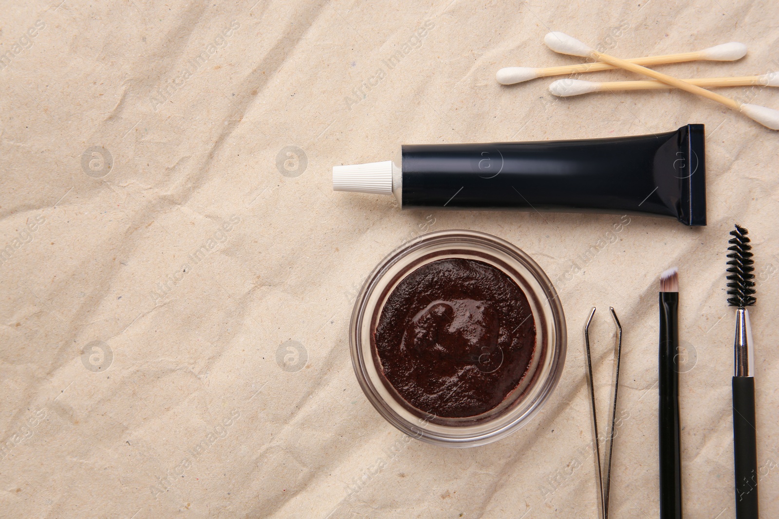 Photo of Flat lay composition with eyebrow henna and tools on crumpled paper. Space for text