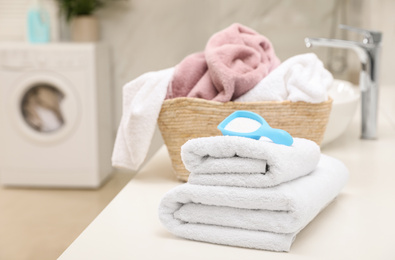 Photo of Clean towels and detergent powder on countertop in bathroom. Space for text