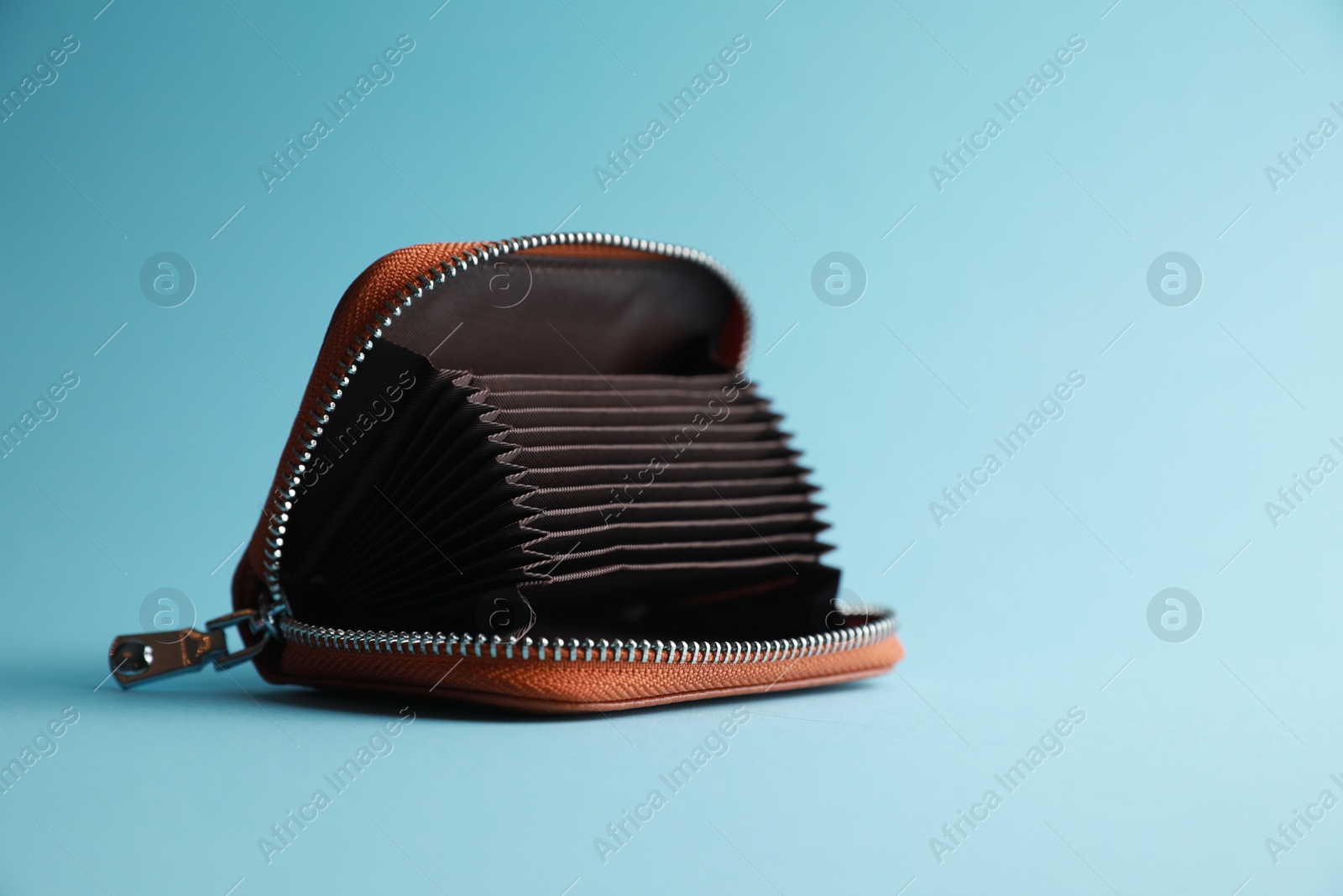 Photo of One open purse on light blue background. Space for text