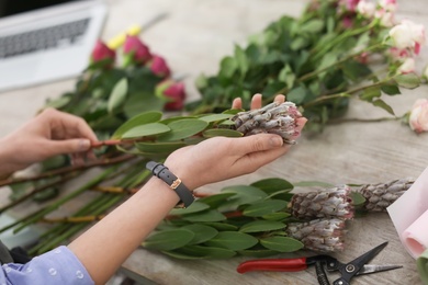 Photo of Female florist making beautiful bouquet in flower shop, closeup