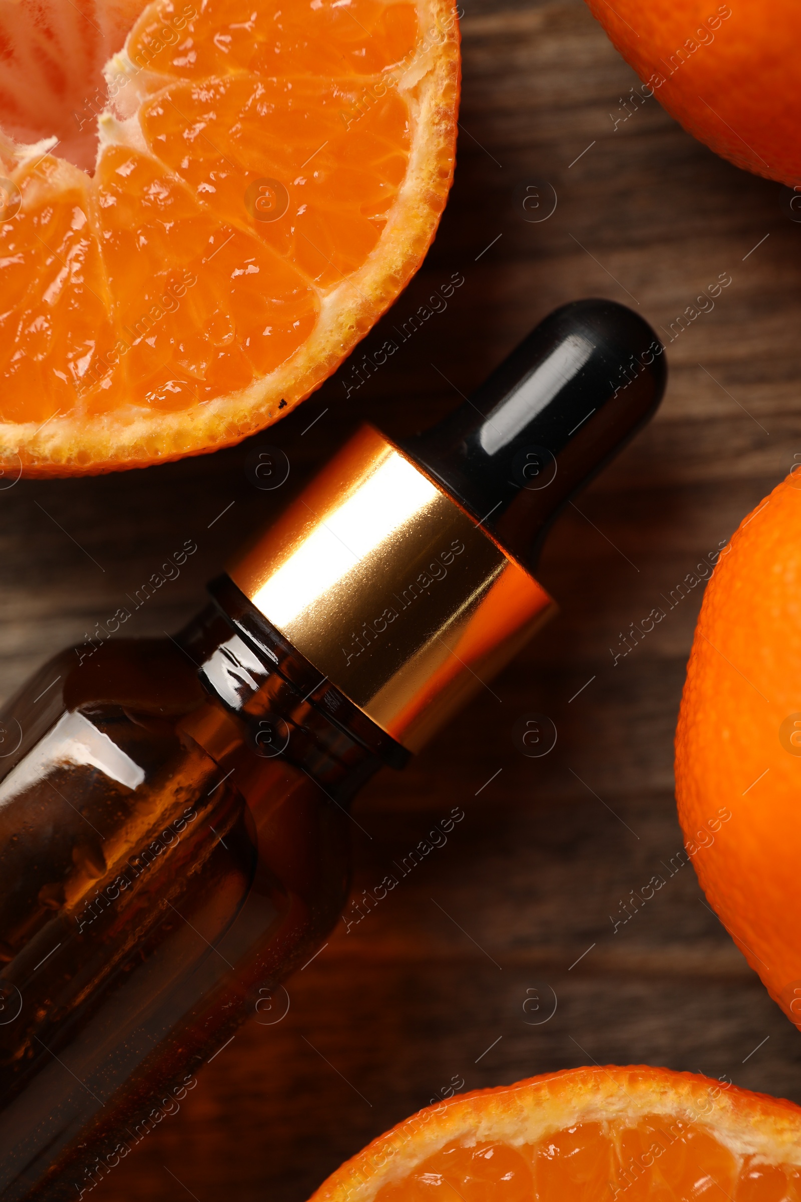 Photo of Bottle of tangerine essential oil and fresh fruits on wooden table, top view