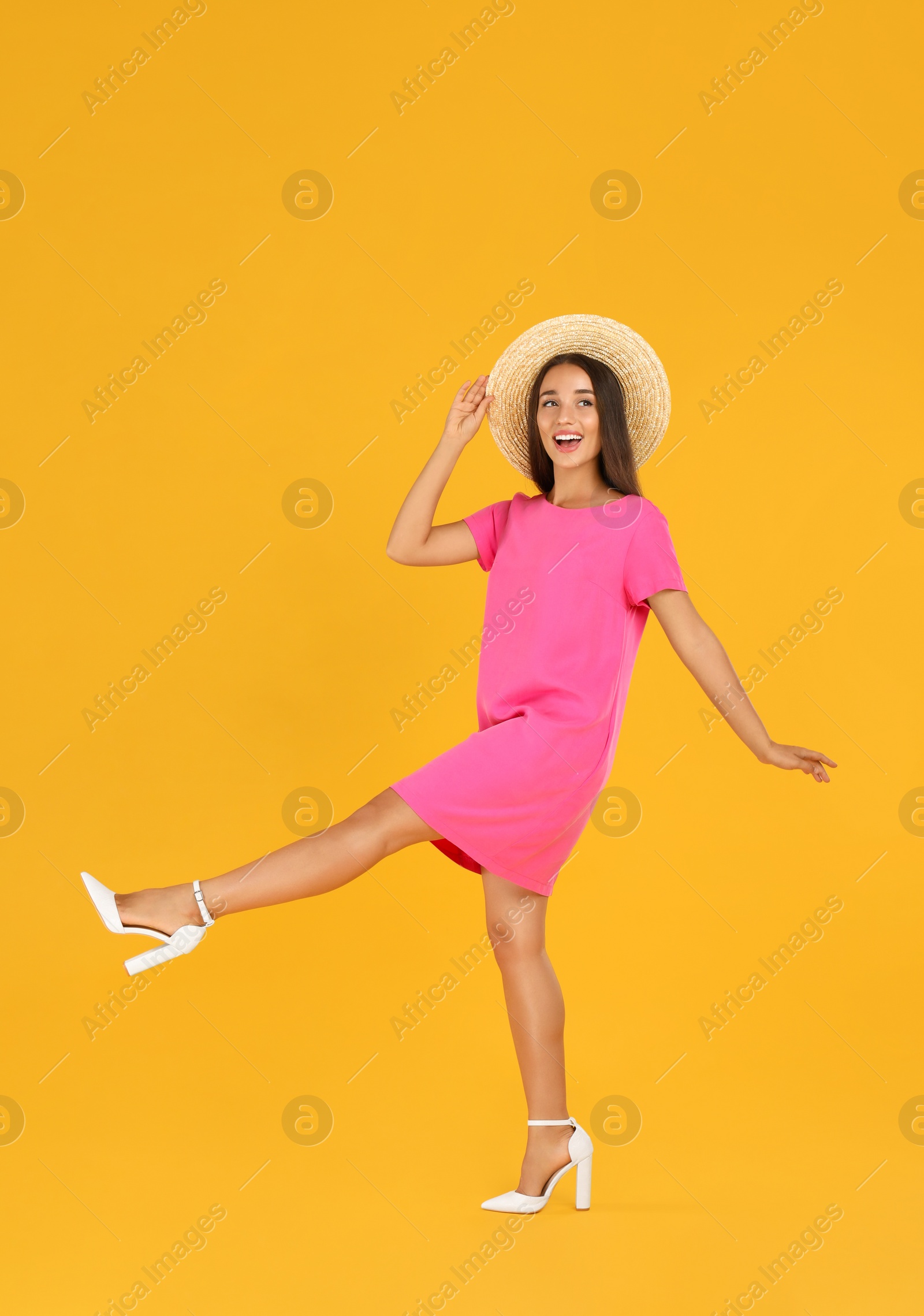 Photo of Young woman wearing stylish pink dress on yellow background