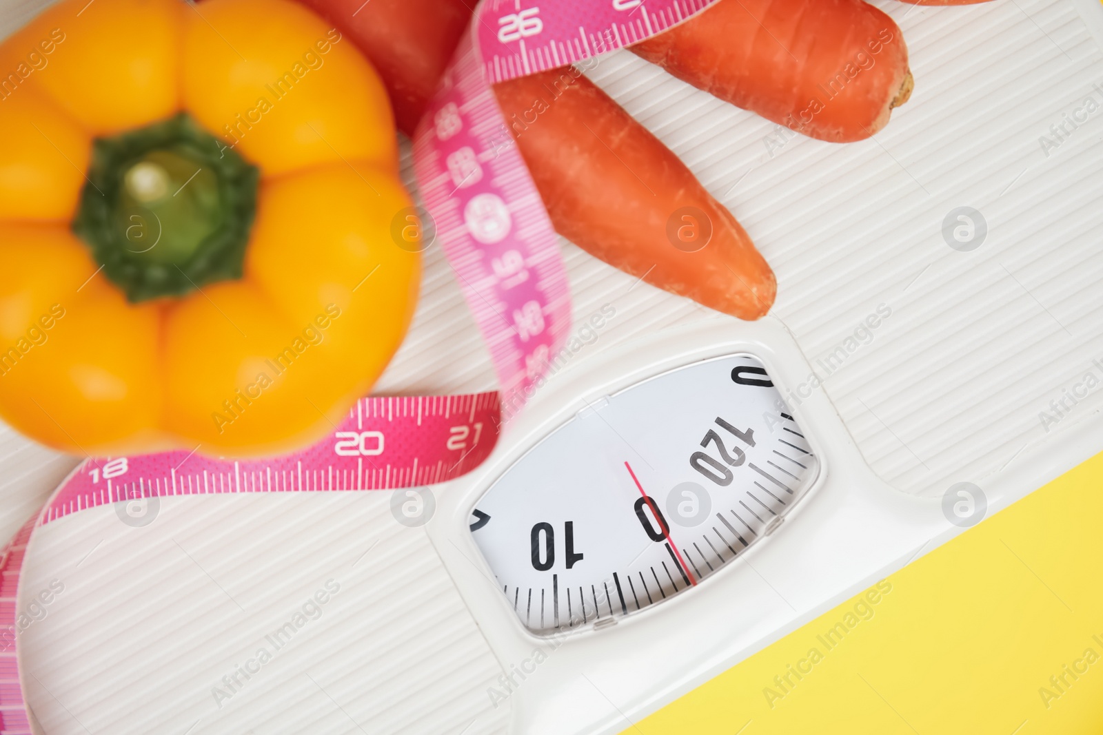 Scales, vegetables and measuring tape on yellow background, top view Photo of Scales, vegetables and measuring tape on yellow background, top view