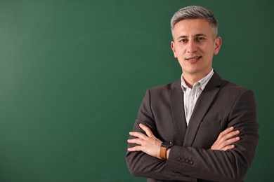 Photo of Teacher with crossed arms near chalkboard, space for text