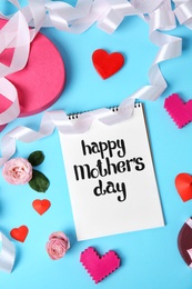 Photo of Notebook with phrase "HAPPY MOTHER'S DAY" and decor on color background