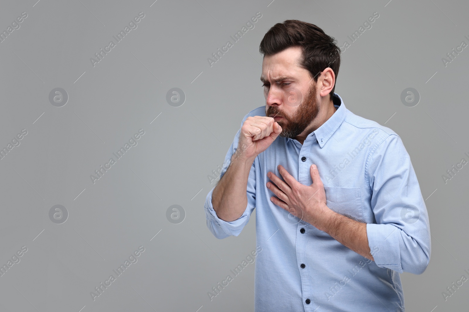 Photo of Sick man coughing on light grey background, space for text. Cold symptoms