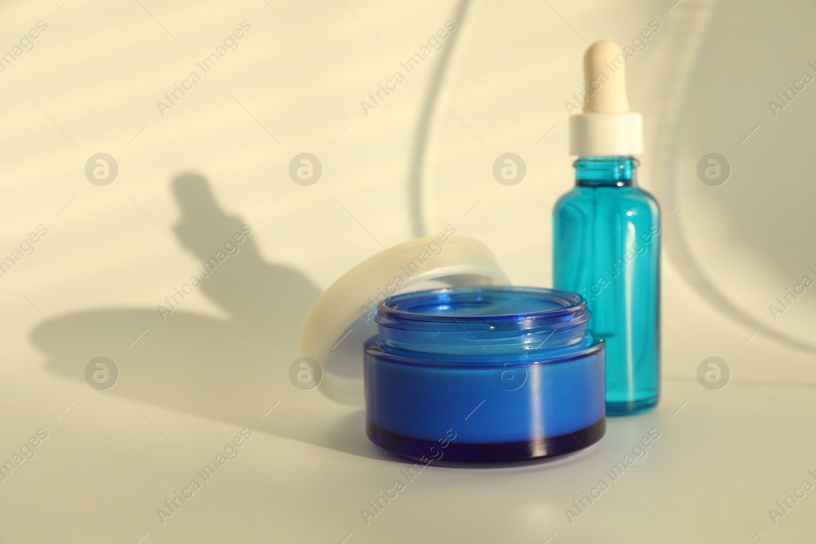 Photo of Bottle and jar with cosmetic products on beige background, space for text