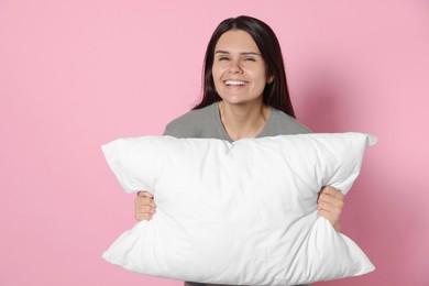 Photo of Happy young woman with soft pillow on pink background