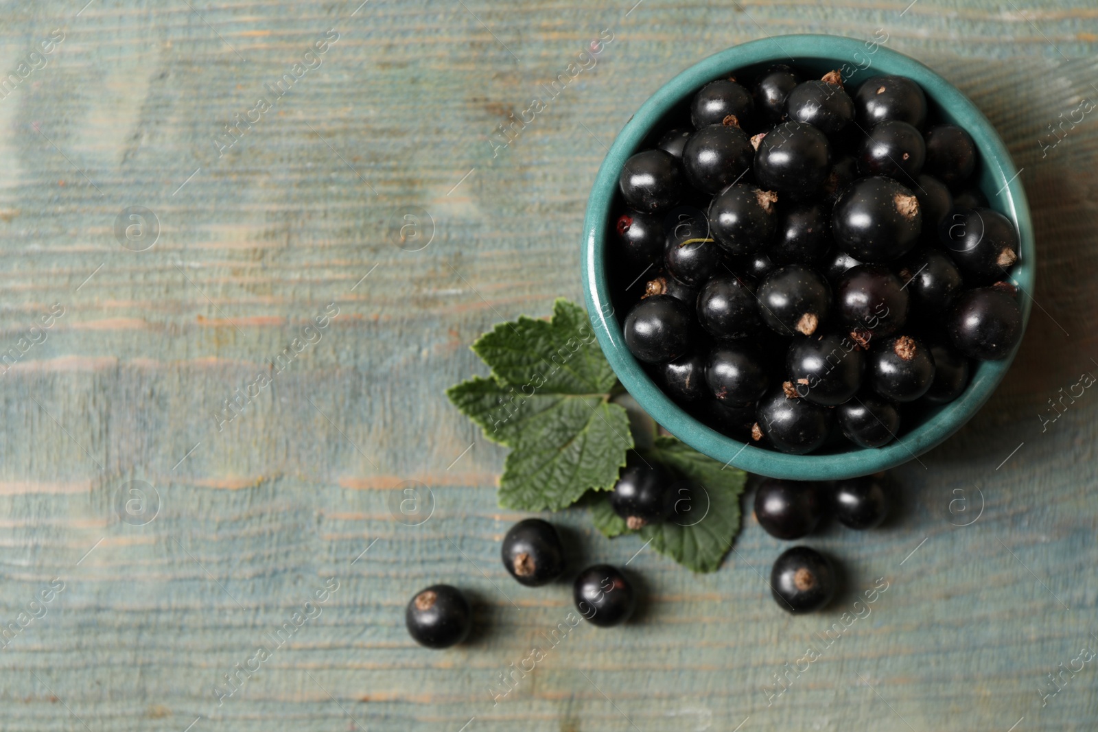 Photo of Ripe blackcurrants and leaves on wooden rustic table, flat lay. Space for text