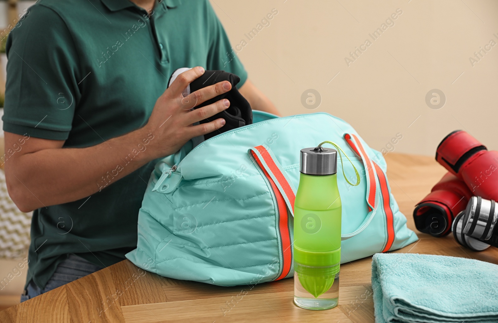 Photo of Man packing sports bag for training indoors, closeup