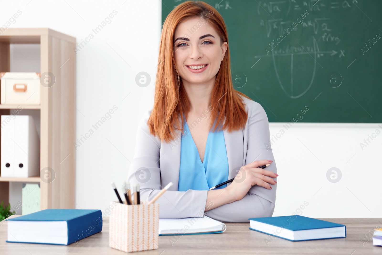 Photo of Beautiful young teacher working at table in classroom