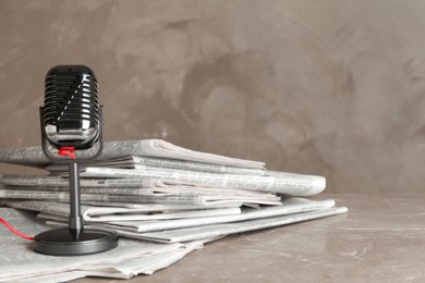 Photo of Newspapers and vintage microphone on marble table. Journalist's work