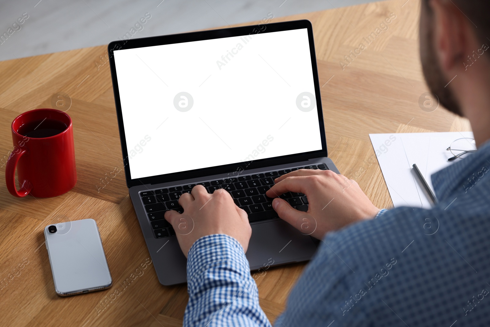 Photo of Man working on laptop at wooden desk, closeup