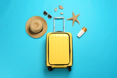 Photo of Flat lay composition with suitcase and beach items on color background