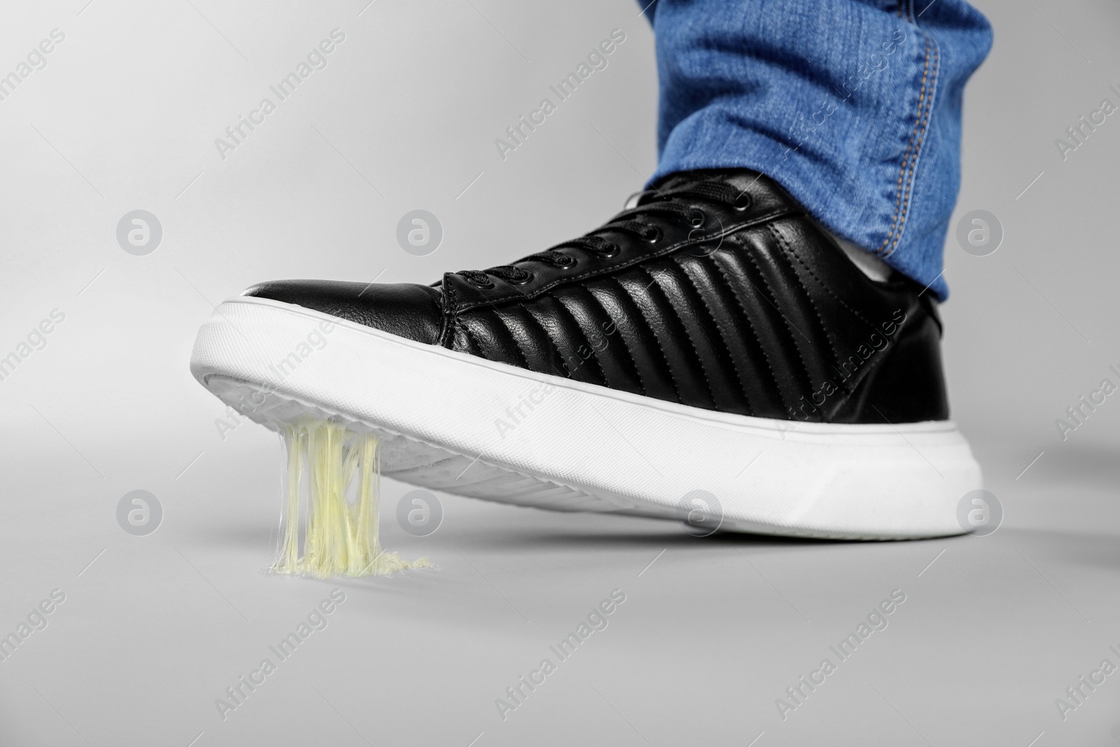 Photo of Man stepping into chewing gum on light grey background, closeup