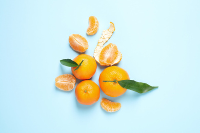 Photo of Flat lay composition with fresh ripe tangerines and leaves on light blue background. Citrus fruit