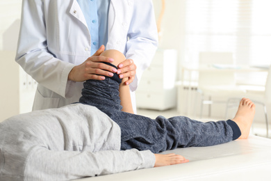 Photo of Professional orthopedist examining little patient's leg in clinic