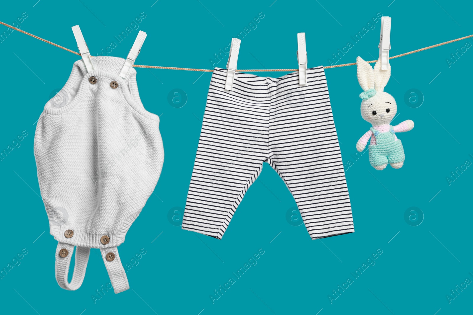 Photo of Baby clothes and crochet toy drying on washing line against turquoise background