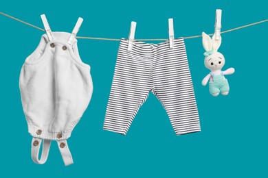 Photo of Baby clothes and crochet toy drying on washing line against turquoise background