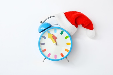 Photo of Alarm clock with Santa hat on white background, top view. New Year countdown