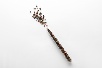 Photo of Glass tube with peppercorns on white background, top view