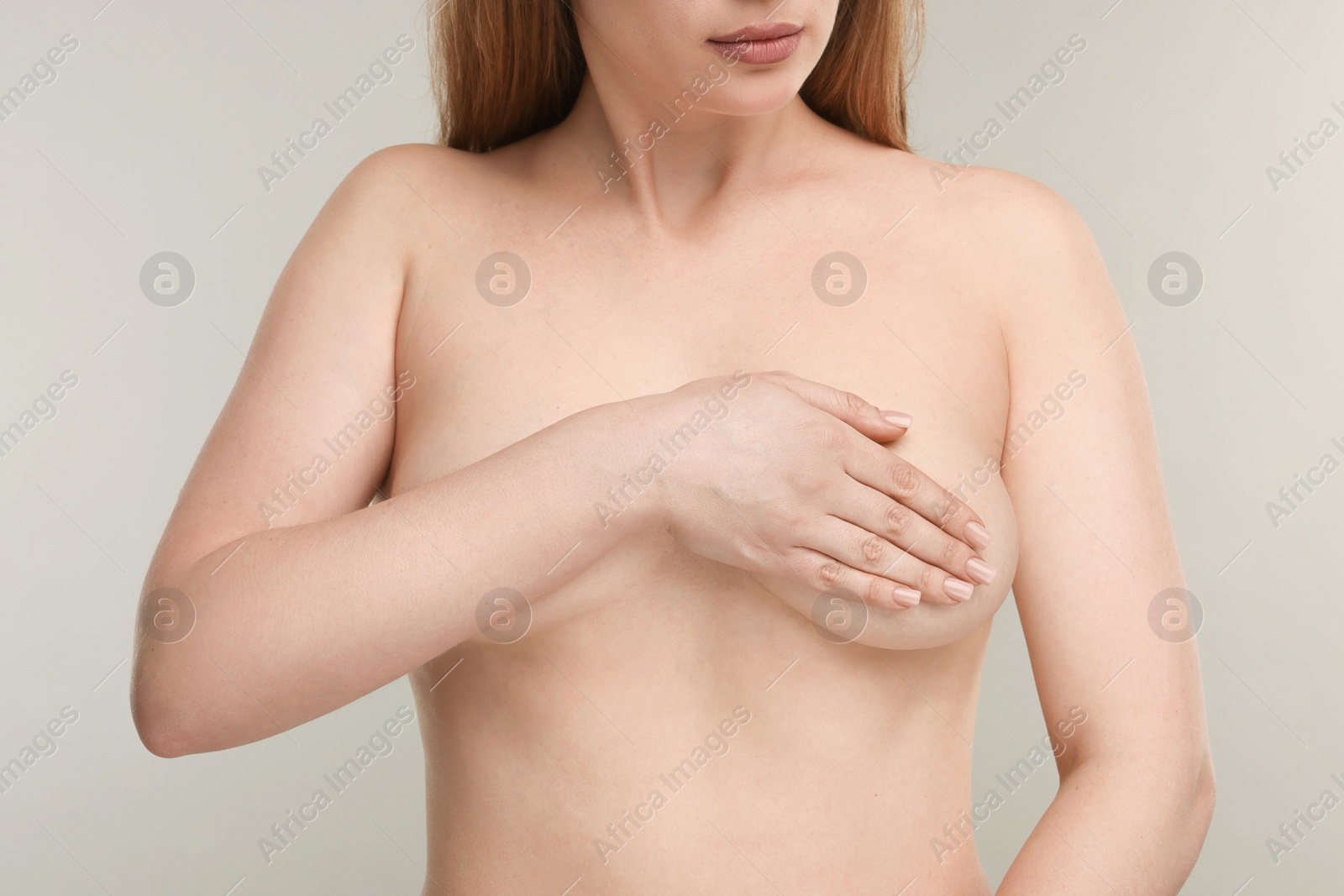 Photo of Mammology. Naked young woman doing breast self-examination on light grey background, closeup