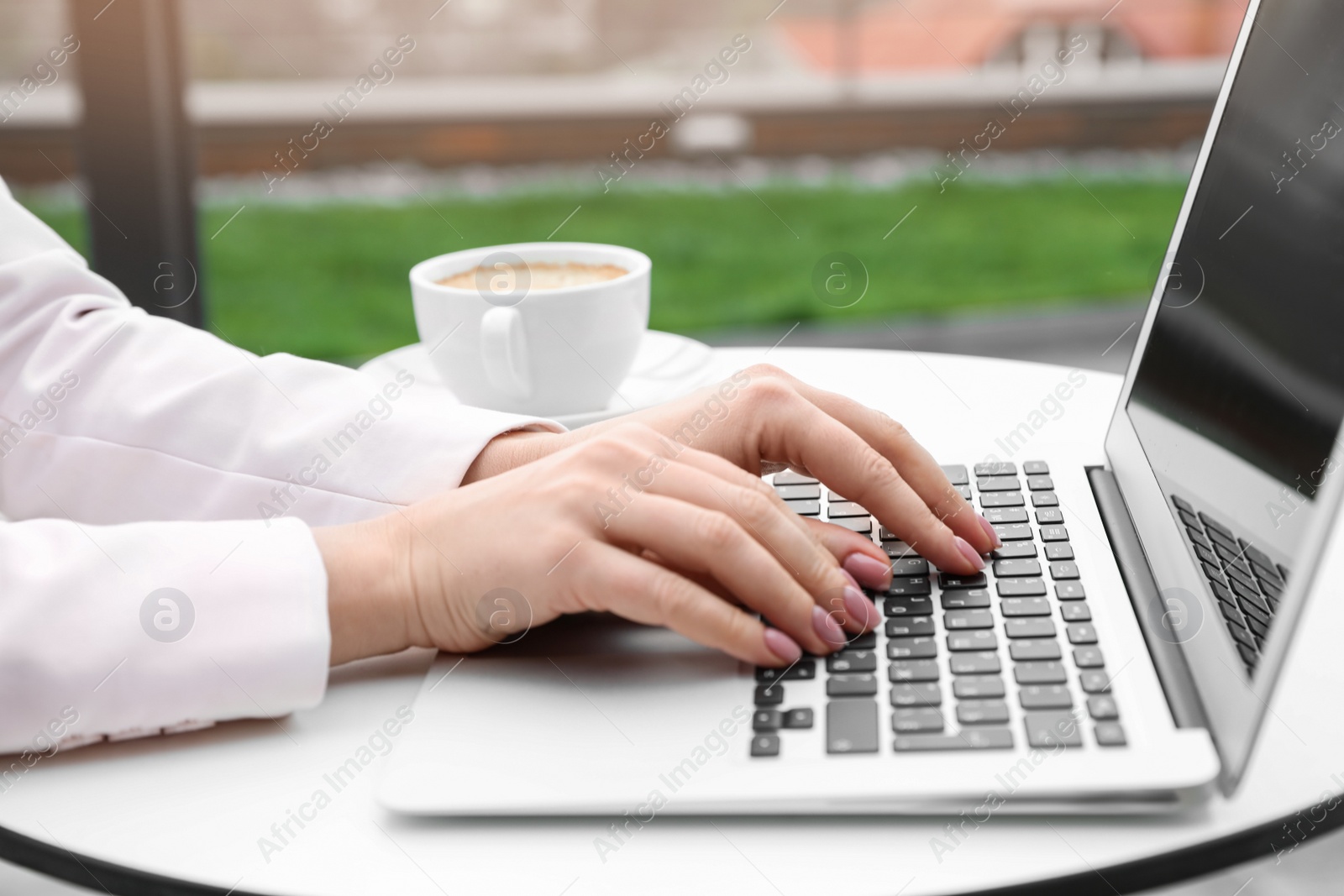 Photo of Businesswoman working with laptop in outdoor cafe, closeup. Corporate blog