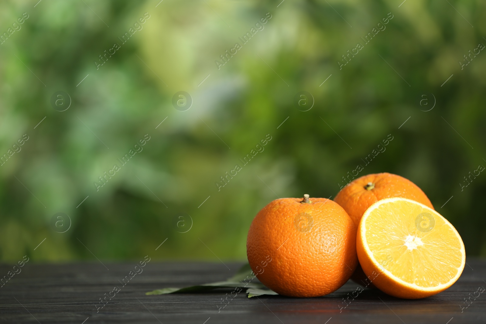 Photo of Fresh ripe oranges on wooden table against blurred background. Space for text