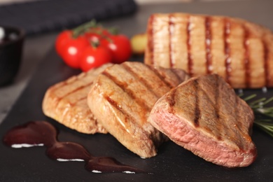 Photo of Grilled meat with sauce on slate plate, closeup