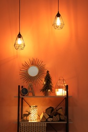 Photo of Shelving unit with Christmas decor and firewood near orange wall. Interior design