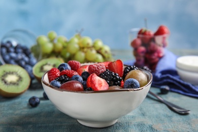 Photo of Fresh tasty fruit salad on wooden table against blue background