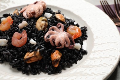 Photo of Delicious black risotto with seafood served on plate, closeup