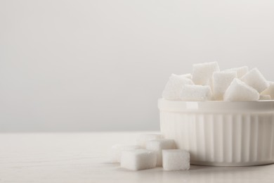 Photo of Bowl with sugar cubes served on white table. Space for text