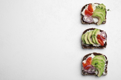 Photo of Delicious avocado sandwiches on white table, flat lay. Space for text