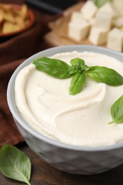 Delicious tofu sauce and basil leaves in bowl on table, closeup