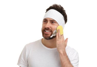 Photo of Man with headband washing his face using sponge on white background