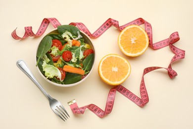 Measuring tape, salad, halves of orange and fork on yellow background, flat lay