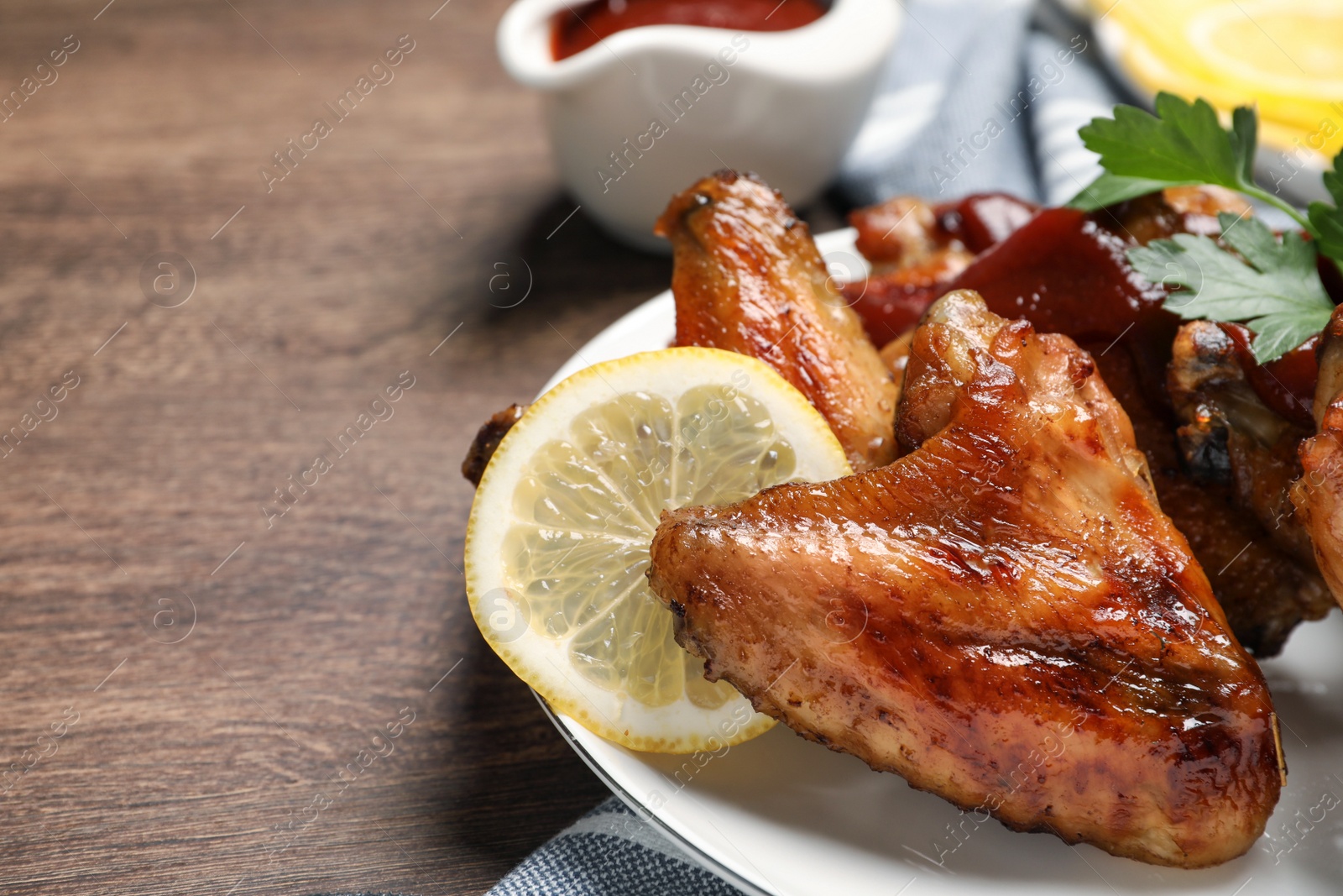 Photo of Delicious fried chicken wings served on wooden table, space for text