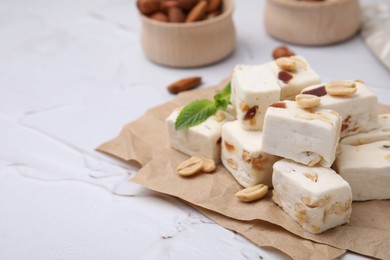 Photo of Pieces of delicious nutty nougat on parchment paper, closeup. Space for text
