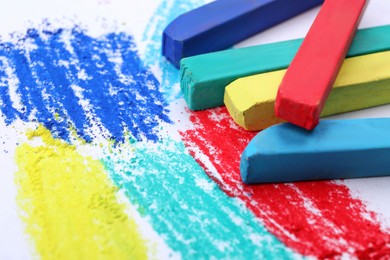 Photo of Colorful pastel chalks on white background, closeup. Drawing materials