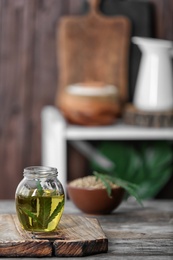 Photo of Jar with hemp oil and fresh leaf on wooden table. Space for text